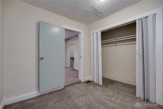 unfurnished bedroom featuring carpet, a textured ceiling, and a closet