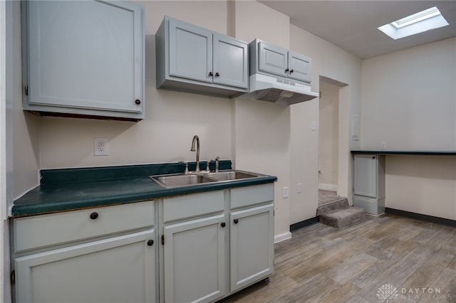 kitchen with a skylight, sink, and light wood-type flooring