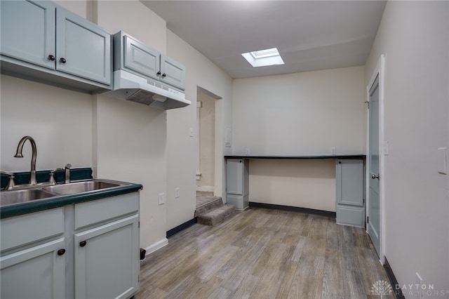 kitchen with light hardwood / wood-style floors, a skylight, and sink