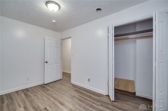 unfurnished bedroom with a textured ceiling, light hardwood / wood-style flooring, and a closet