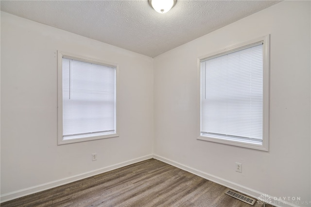 spare room with a textured ceiling and dark wood-type flooring