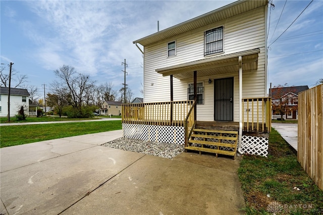 rear view of house featuring a lawn and a porch