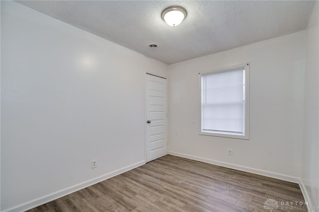 empty room featuring a textured ceiling and hardwood / wood-style flooring