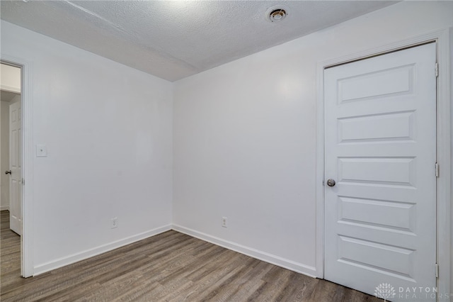 spare room with a textured ceiling and hardwood / wood-style flooring