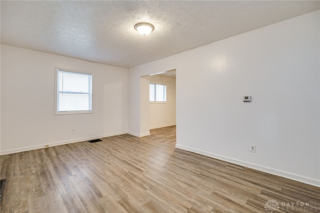 unfurnished room featuring light wood-type flooring and a textured ceiling