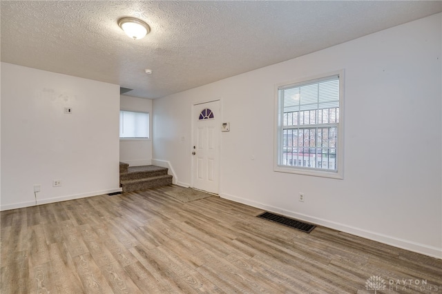 entryway with light wood-type flooring and a textured ceiling