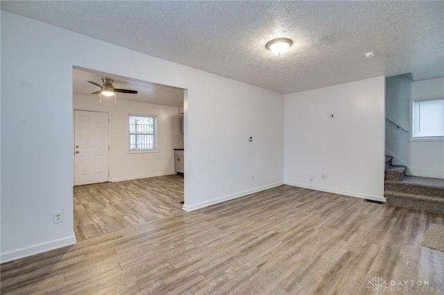 unfurnished room with ceiling fan, plenty of natural light, a textured ceiling, and light hardwood / wood-style flooring