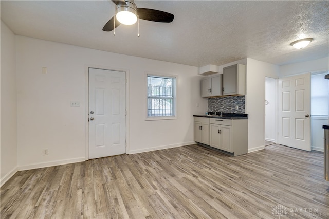 kitchen featuring gray cabinets, ceiling fan, light hardwood / wood-style flooring, and decorative backsplash