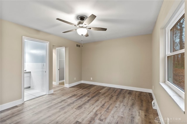 unfurnished bedroom featuring ensuite bath, ceiling fan, and light wood-type flooring