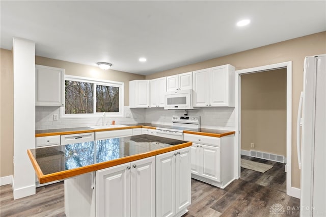 kitchen featuring white appliances, dark wood-type flooring, sink, white cabinets, and a kitchen island