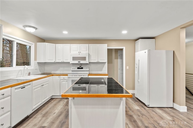 kitchen featuring white cabinetry, a center island, white appliances, and sink