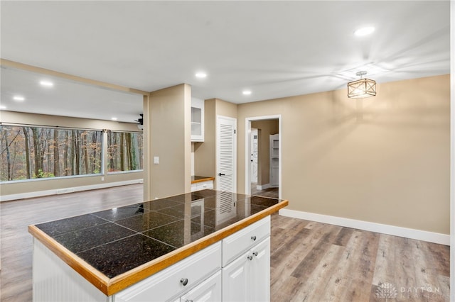 kitchen featuring white cabinets, a center island, light hardwood / wood-style floors, and ceiling fan