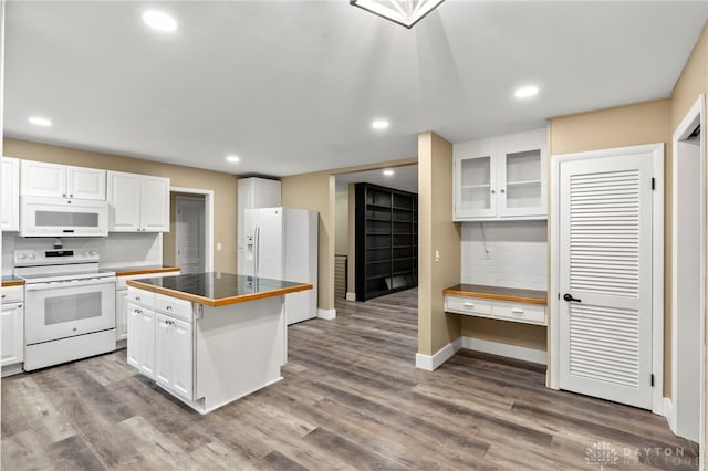 kitchen with backsplash, white appliances, a kitchen island, hardwood / wood-style floors, and white cabinetry