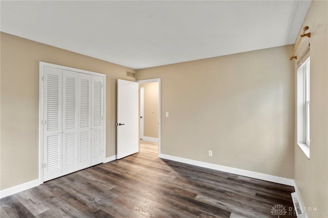 unfurnished bedroom with a closet and dark wood-type flooring