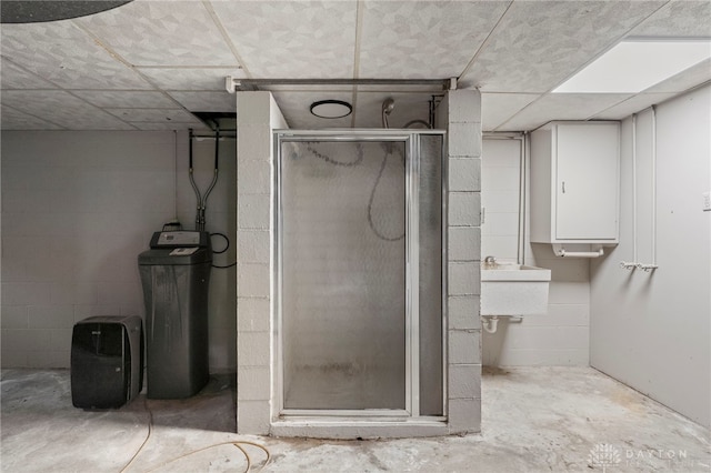 bathroom with a shower with door, sink, and concrete floors