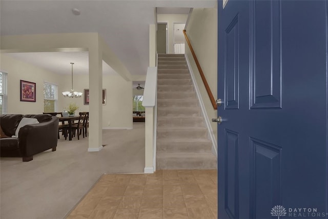 foyer entrance with light colored carpet and an inviting chandelier