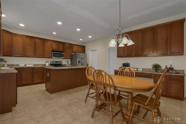 kitchen with a kitchen island, hanging light fixtures, appliances with stainless steel finishes, and an inviting chandelier