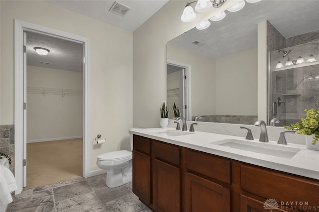 bathroom with a textured ceiling, vanity, an enclosed shower, and toilet