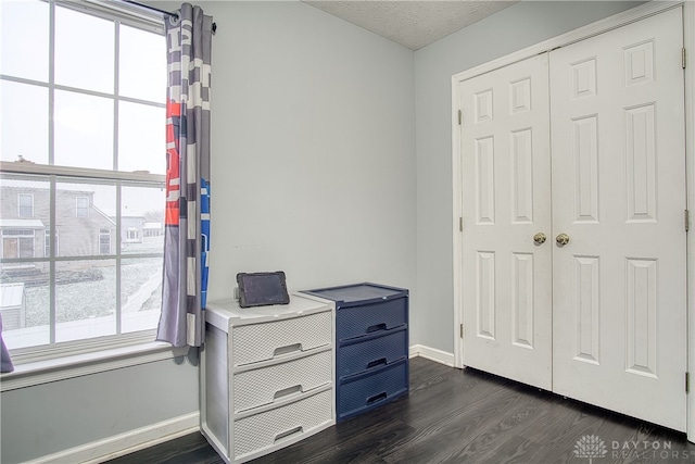 bedroom featuring a textured ceiling, multiple windows, a closet, and dark hardwood / wood-style floors