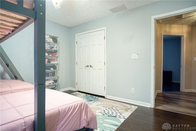 bedroom featuring a textured ceiling, ceiling fan, dark wood-type flooring, and a closet