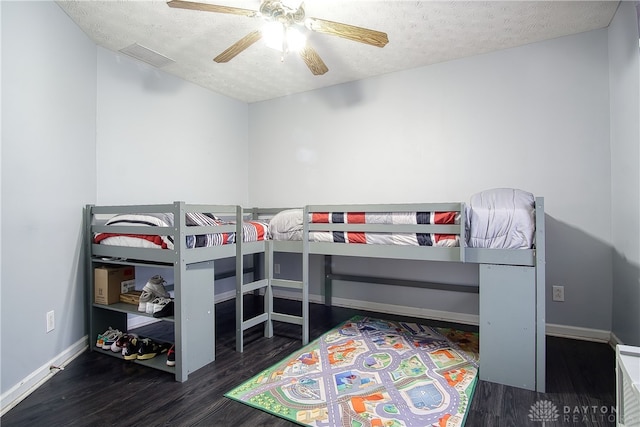 bedroom with a textured ceiling, ceiling fan, and dark wood-type flooring