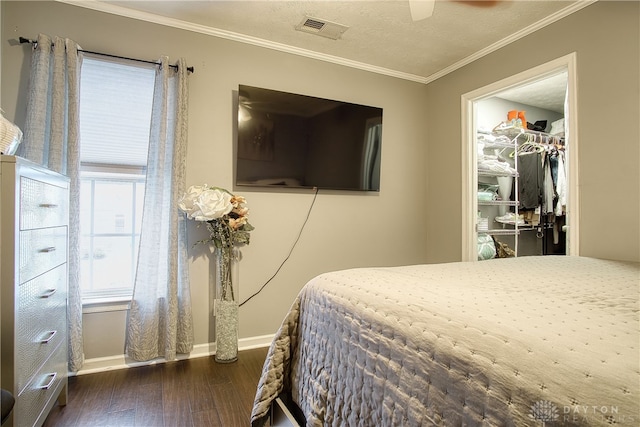 bedroom featuring ceiling fan, dark hardwood / wood-style flooring, a textured ceiling, and ornamental molding