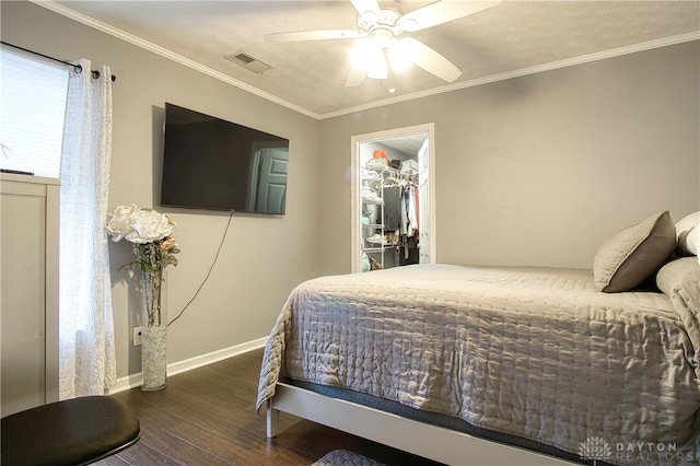 bedroom with ornamental molding, a spacious closet, ceiling fan, and dark wood-type flooring