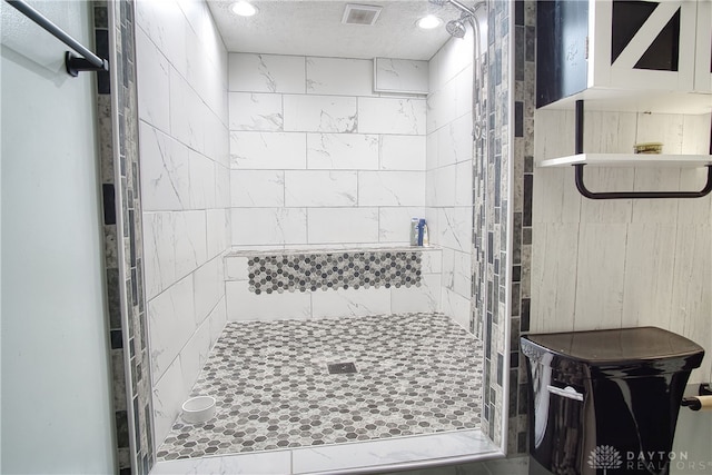 bathroom featuring a tile shower and a textured ceiling