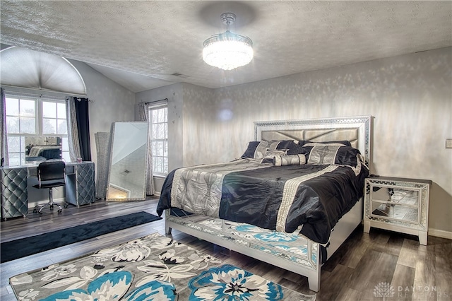 bedroom with a textured ceiling, multiple windows, wood-type flooring, and lofted ceiling