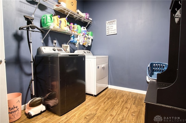 clothes washing area with washer and dryer and light wood-type flooring