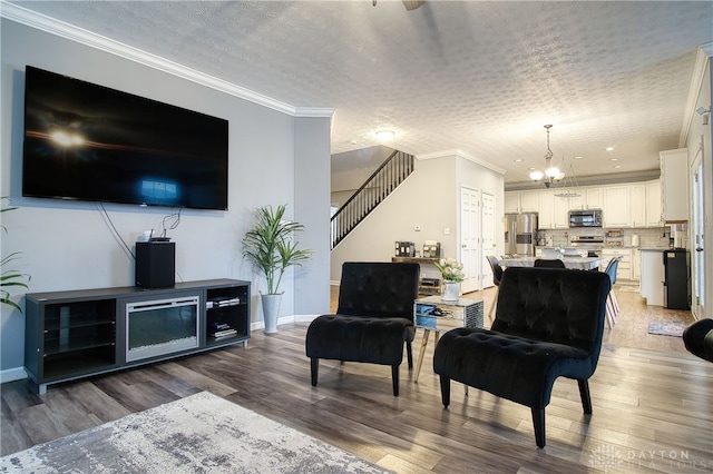 living room featuring a chandelier, ornamental molding, a textured ceiling, and dark wood-type flooring