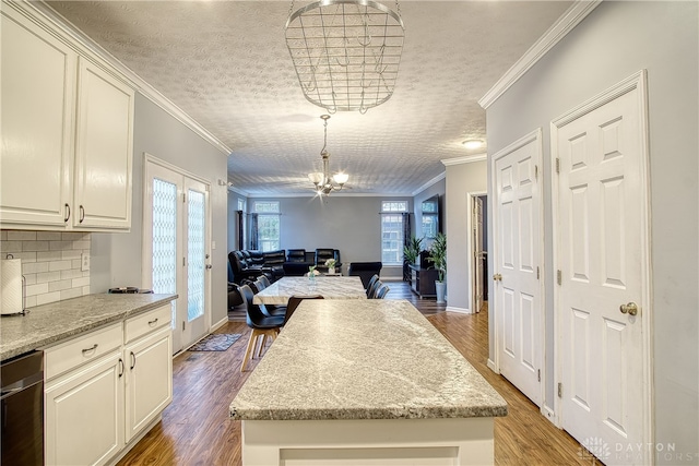 kitchen featuring hardwood / wood-style flooring, light stone countertops, and crown molding