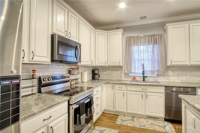 kitchen with sink, white cabinets, ornamental molding, and appliances with stainless steel finishes