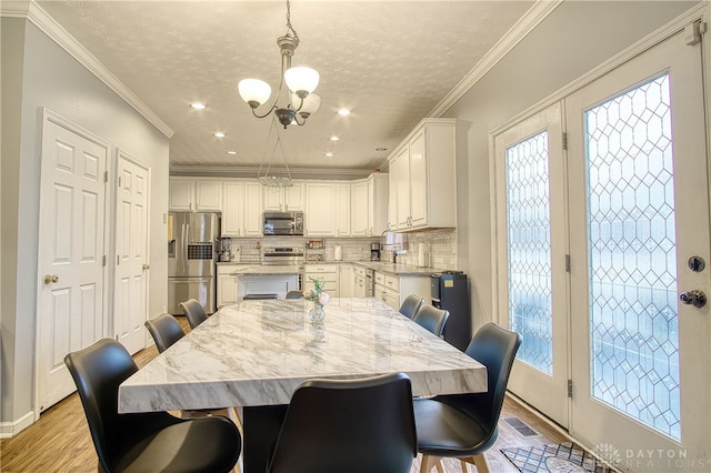 dining room featuring a chandelier, crown molding, light hardwood / wood-style floors, and a textured ceiling