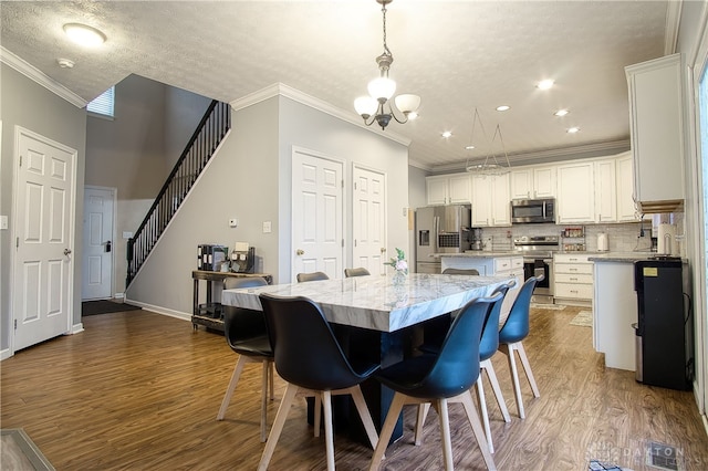 kitchen with white cabinetry, hanging light fixtures, stainless steel appliances, dark hardwood / wood-style flooring, and a kitchen island