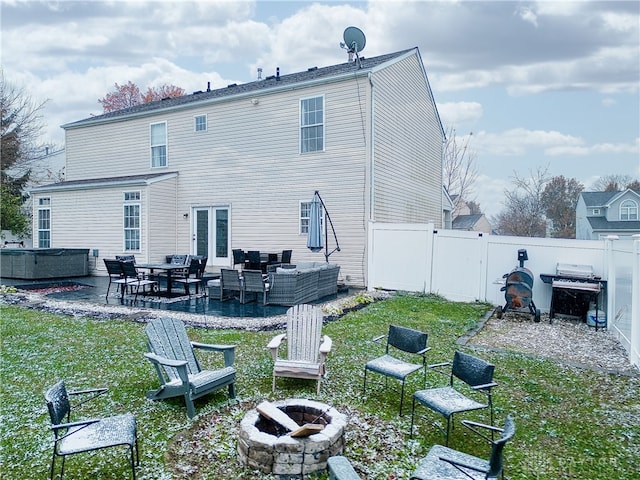 back of house featuring a lawn, an outdoor living space with a fire pit, and a patio