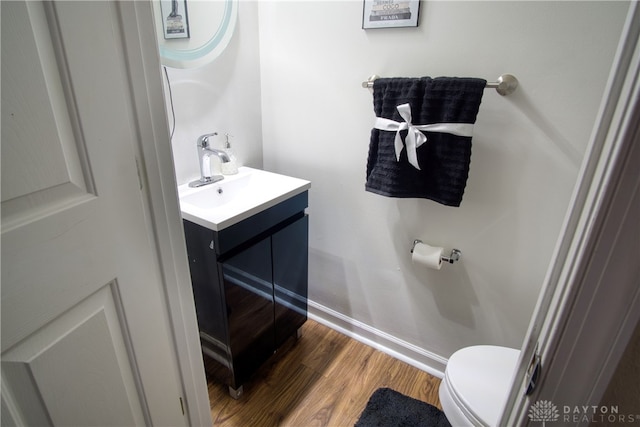 bathroom with toilet, vanity, and hardwood / wood-style flooring