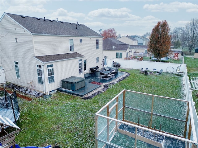 rear view of property featuring a patio, a yard, and a hot tub