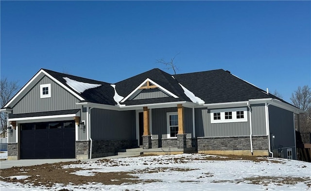 view of front of house featuring a garage, stone siding, and covered porch