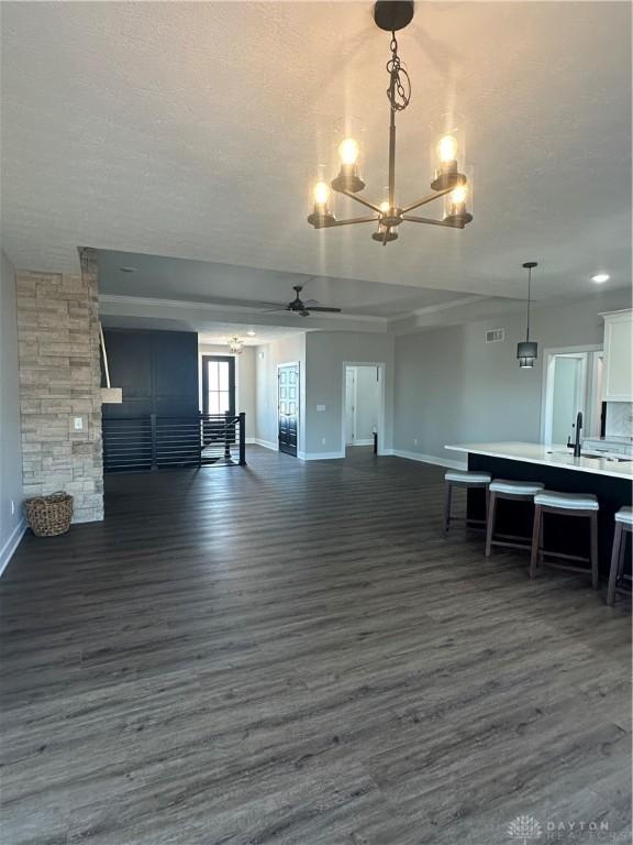 interior space featuring dark wood-style floors, baseboards, a textured ceiling, and ceiling fan with notable chandelier