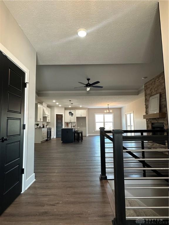 corridor with baseboards, dark wood-type flooring, a textured ceiling, an upstairs landing, and a chandelier