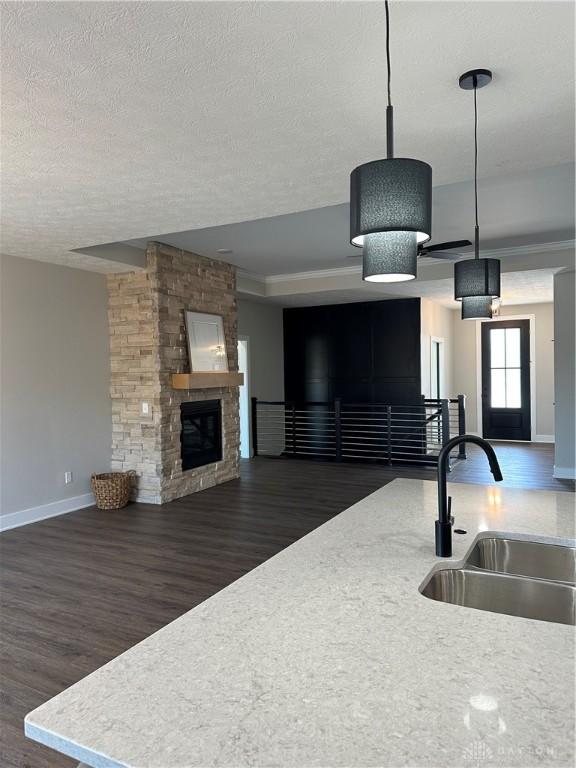 kitchen featuring dark wood-style floors, open floor plan, decorative light fixtures, light countertops, and a sink