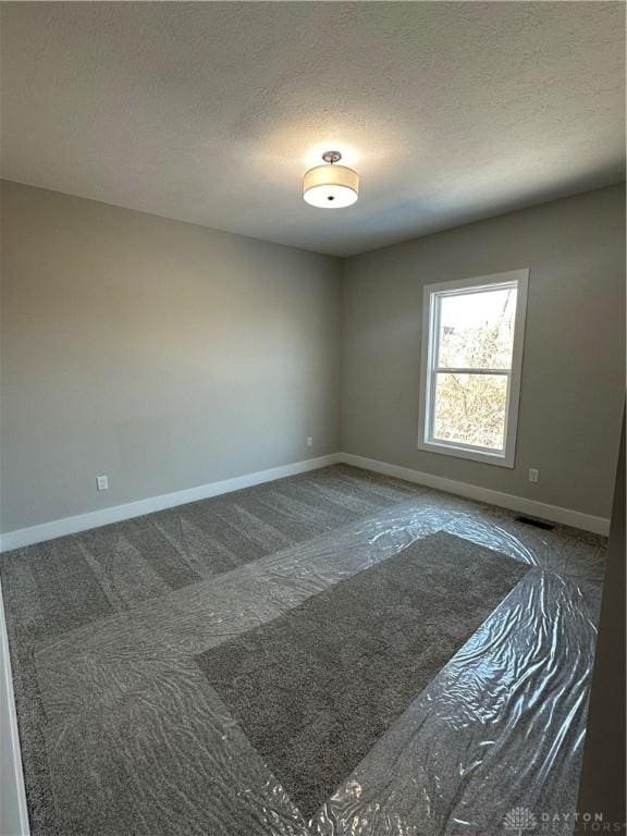 carpeted empty room with visible vents, baseboards, and a textured ceiling