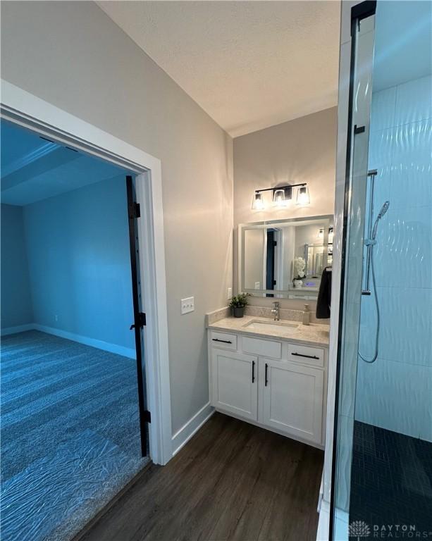 full bath with wood finished floors, walk in shower, vanity, and baseboards