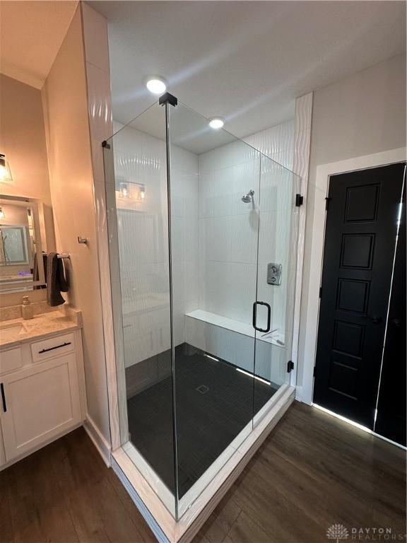 full bathroom with a shower stall, wood finished floors, and vanity