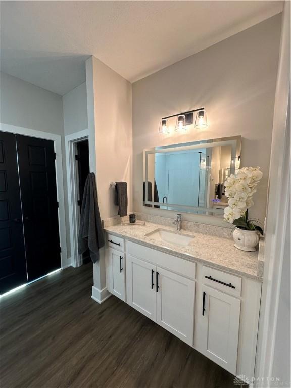 bathroom with wood finished floors, vanity, and baseboards