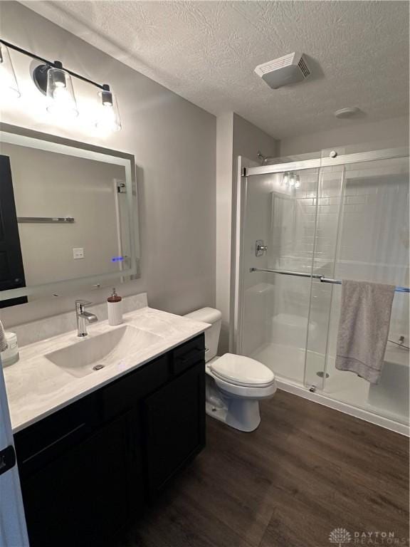 full bath with toilet, wood finished floors, vanity, visible vents, and a shower stall