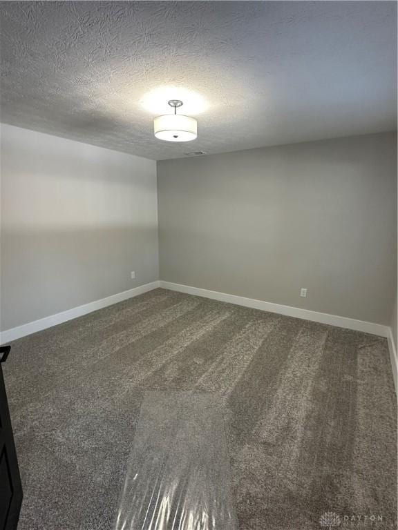 carpeted spare room with baseboards and a textured ceiling