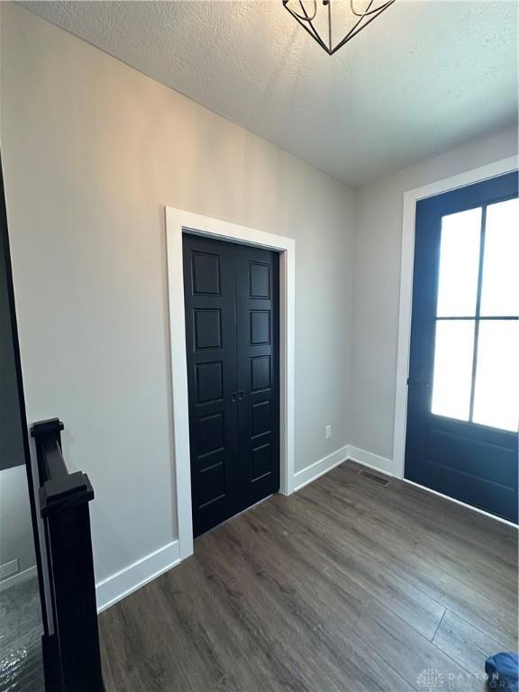 foyer entrance featuring a textured ceiling, dark wood finished floors, and baseboards