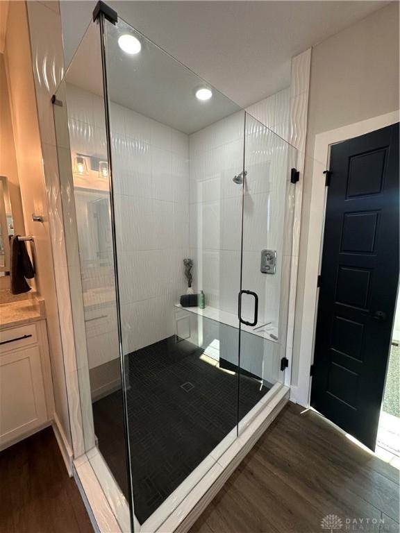 full bath with a stall shower, recessed lighting, and wood finished floors